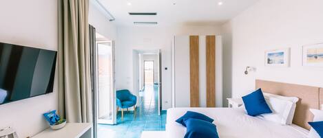 Une chambre d’hôtel moderne dotée d’un grand lit, d’une télévision à écran plat, d’un bureau avec un ordinateur et d’une chaise.
