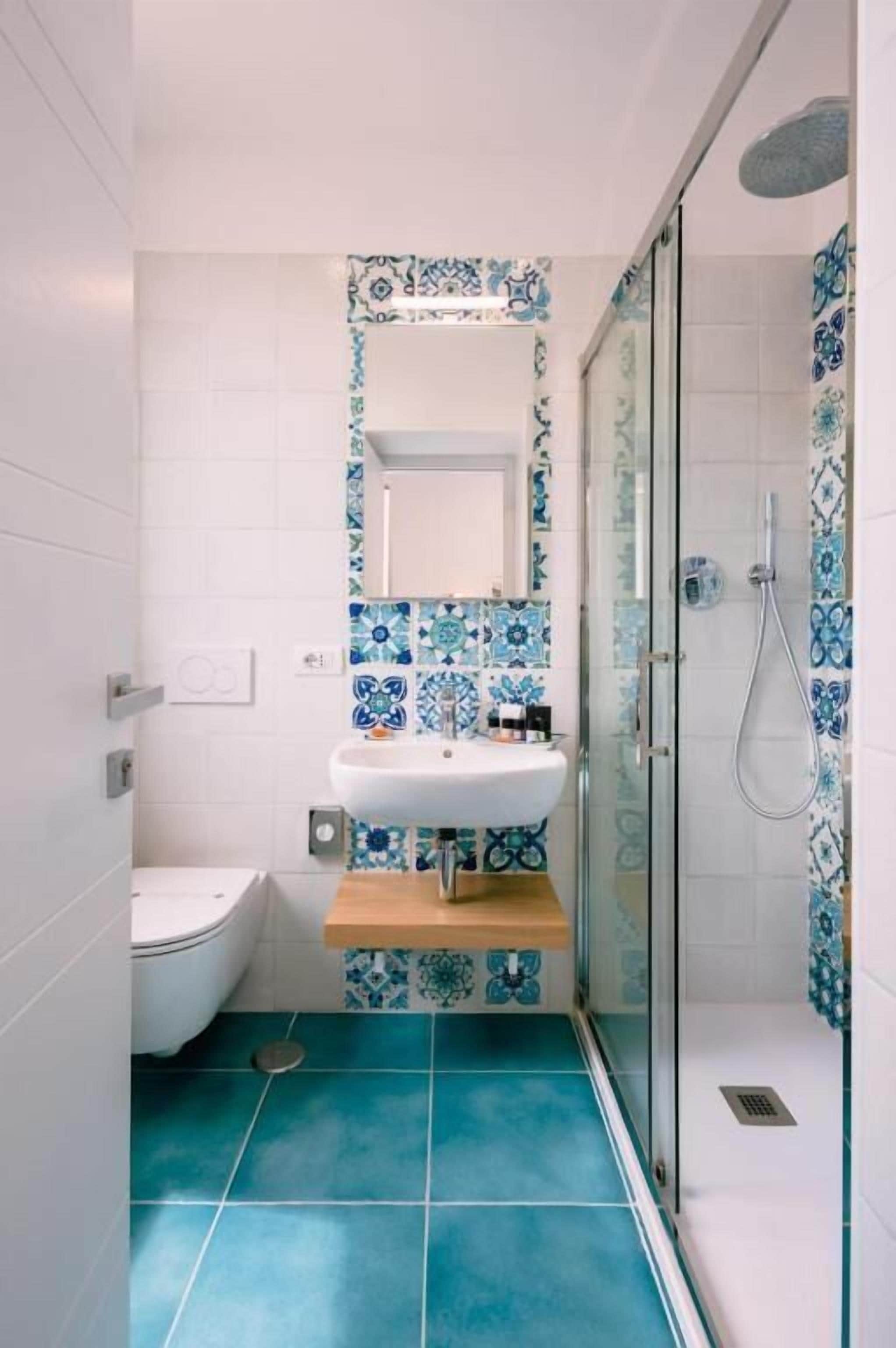 Un baño con lavamanos blanco, inodoro y zona de ducha.