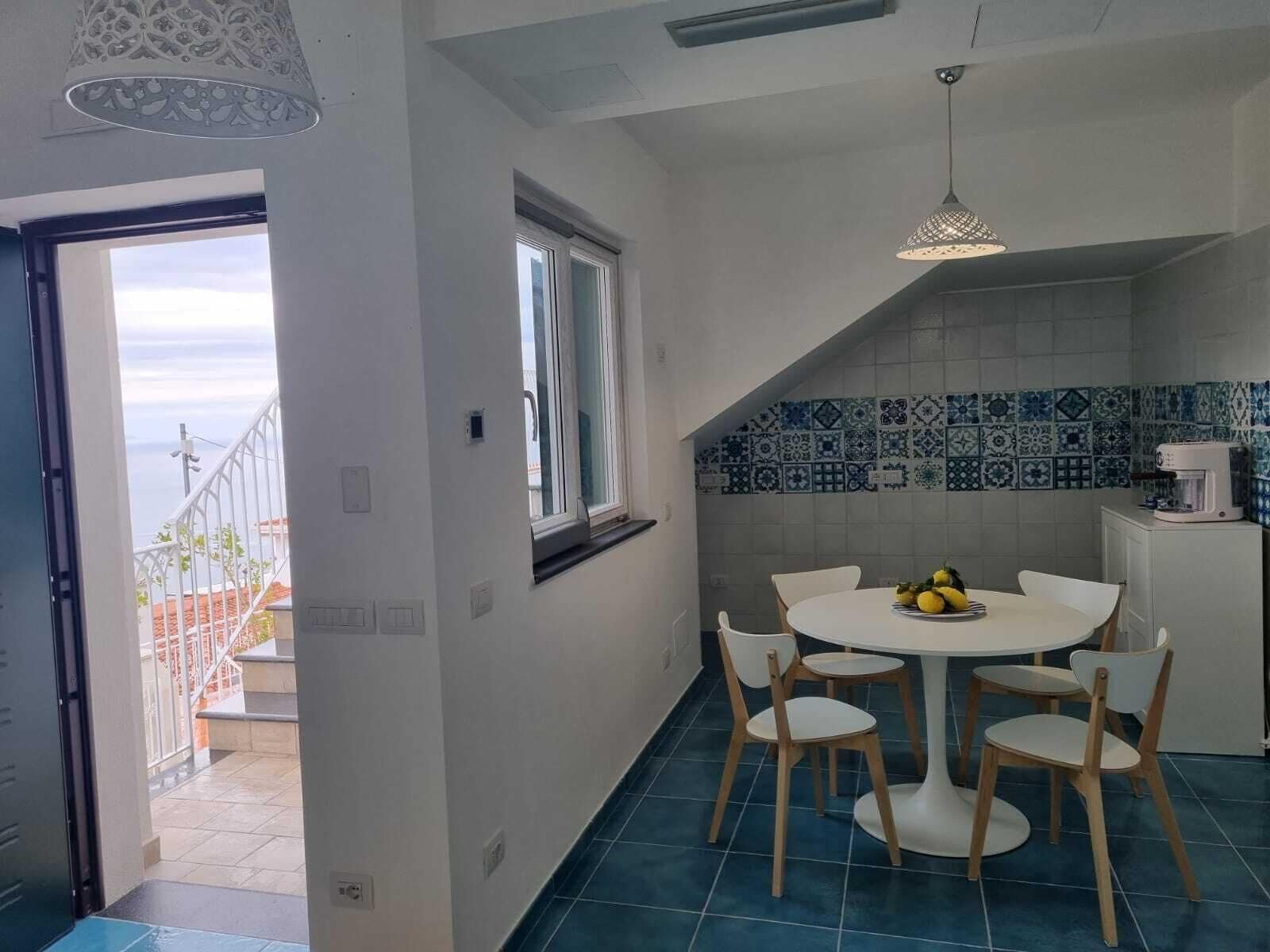 A kitchen with a round table and chairs, a window, and a view of the outside.