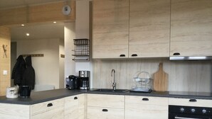 A modern kitchen with light wood cabinetry, a stainless steel sink, and a black oven. - New! Superb apartment of 90 m2 in the heart of Font Romeu (Font-Romeu-Odeillo-Via)