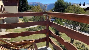 A wooden deck with a bench and a sign, overlooking a grassy area and a road with a car. - New! Superb apartment of 90 m2 in the heart of Font Romeu (Font-Romeu-Odeillo-Via)