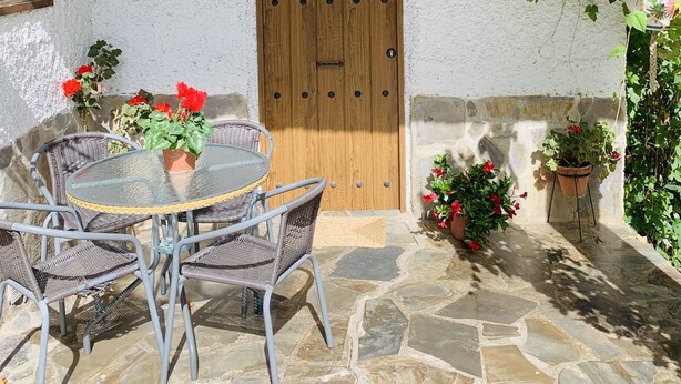 A patio with a wooden door, stone flooring, and wicker chairs. - Self catering Barranco de la Salud for 4 people (Nevada)