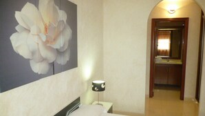 Une chambre d’hôtel avec un lit, une table de chevet, une lampe et une grande œuvre d’art florale accrochée au mur.