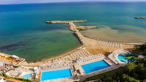An aerial view of a resort with multiple swimming pools, a beach area, and a water slide.