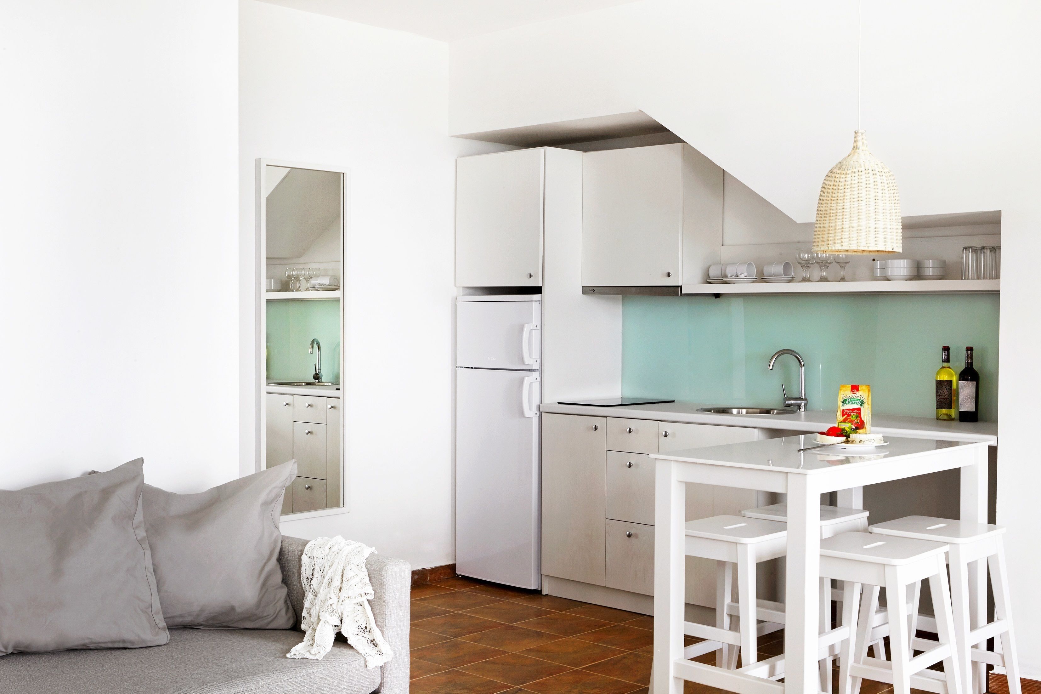 A modern kitchen with white cabinets, a dining table, and bar stools.