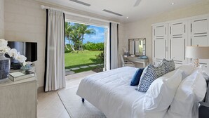 A spacious bedroom with a large bed, a desk, and a television. - Windfall, Westland Heights - Exclusive 5 bedroom villa, private chef (Westmoreland)