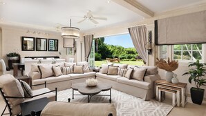 A spacious living room with a large sectional sofa, a coffee table, and a dining area with a table and chairs. - Windfall, Westland Heights - Exclusive 5 bedroom villa, private chef (Westmoreland)