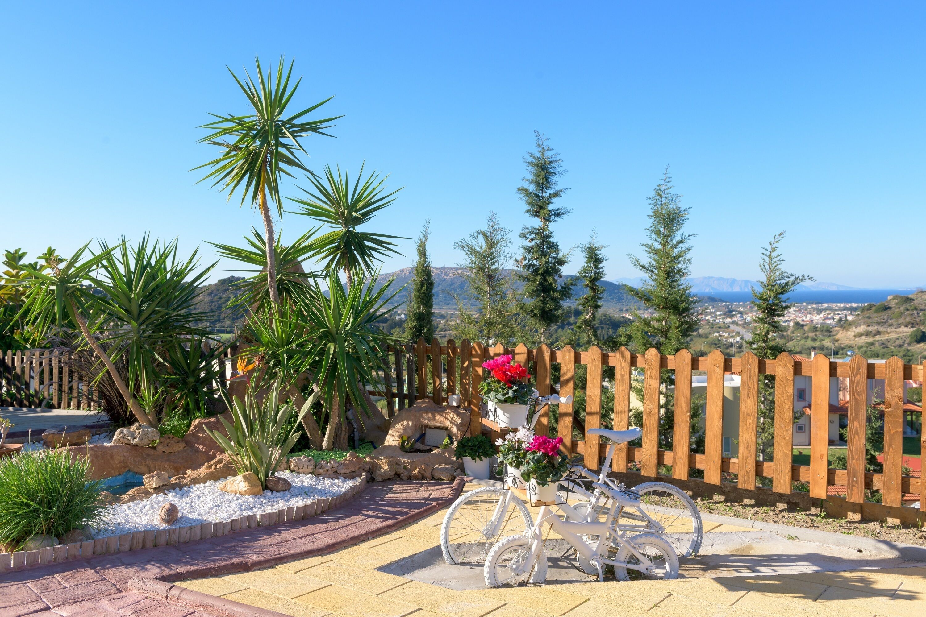A patio area with a wooden fence, a bicycle, and potted plants.