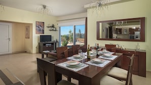 A dining area with a table set for four, a television, and a view of the outdoors. - Dreamcatcher Villa with private pool (Pastida)