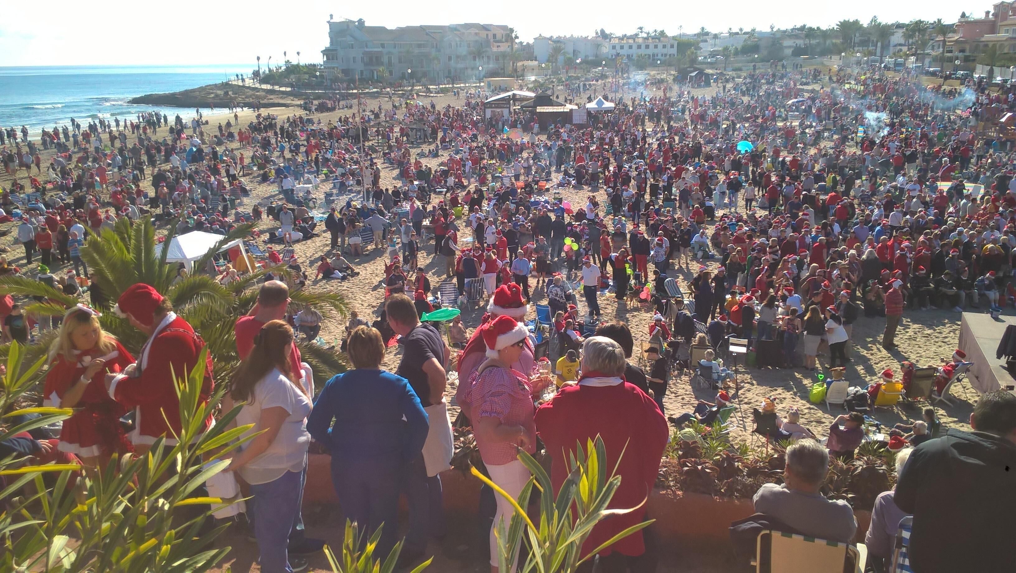 Una spiaggia affollata con persone vestite di rosso, che suggerisce un'atmosfera festosa.