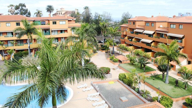 Un hôtel à plusieurs étages, doté de piscines extérieures et bordé de palmiers.