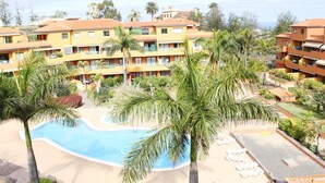 Un complexe hôtelier comprenant des bâtiments à plusieurs étages, une piscine, des palmiers et des chaises longues.