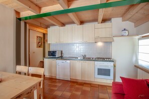 Une cuisine compacte avec des meubles de rangement en bois, un four encastré et un lave-vaisselle.