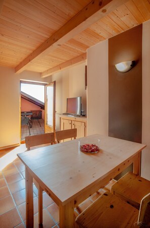 Ein Holzespeisesaal mit Stühlen, ein Fernseher auf einem Schrank und ein Fenster mit Blick ins Freie.