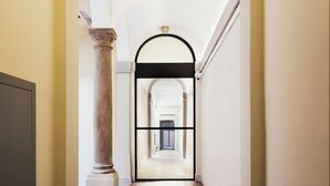 Un pasillo de estilo arquitectónico clásico, con una columna de mármol y un arco que da a otra habitación.