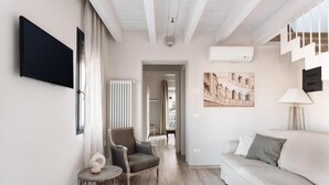 Una sala de estar moderna con un sofá, un sillón, una mesita y un televisor montado en la pared.