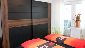 Ein Schlafzimmer mit einem Bett, einem hölzernen Kopfteil und Blick ins Freie.