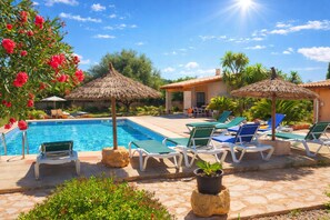 A poolside area with lounge chairs, a swimming pool, and thatched umbrellas.
