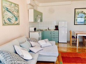 A compact living space with a sofa, a dining table, and a kitchenette.
