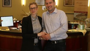Two people standing at a reception desk in a hotel lobby. - Kurhotel Fürstenhof (Blankenburg)