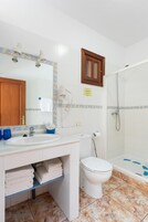 Un baño con lavamanos blanco, inodoro y ducha.
