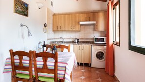 Une cuisine compacte avec des meubles en bois, un four à micro-ondes et un lave-linge.