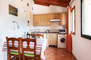 Una cocina compacta con armarios de madera, microondas y lavadora.