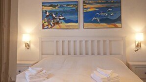 A neatly made bed with folded towels, a white headboard, and two wall-mounted paintings depicting seascapes. - Elbtalauen, comfortable 4* vacation home with 2 separate apartments of 100 m² each (Pinnau)