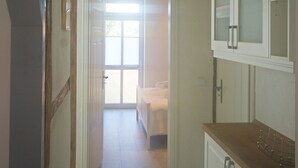 A narrow hallway with wooden beams on the ceiling, a white door leading to a room with a bed, and white cabinets with glass doors. - Elbtalauen, comfortable 4* vacation home with 2 separate apartments of 100 m² each (Pinnau)