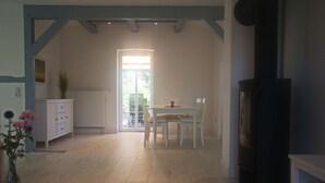 A spacious room with a wooden floor, a dining table with chairs, a white cabinet, and a black fireplace. - Elbtalauen, comfortable 4* vacation home with 2 separate apartments of 100 m² each (Pinnau)