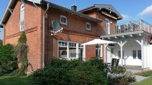 A two-story brick house with a balcony, satellite dish, and outdoor seating area. - Elbtalauen, comfortable 4* vacation home with 2 separate apartments of 100 m² each (Pinnau)