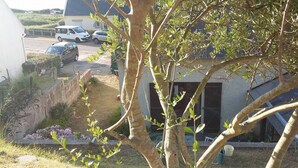 Un quartier résidentiel avec une maison, des voitures garées et un jardin.