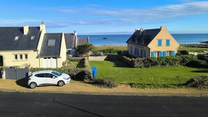 Un quartier résidentiel en bord de mer, avec des maisons, une voiture et une vue sur la mer.