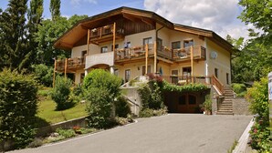 A two-story chalet with a wooden balcony, stone steps, and a garden with various plants and flowers. - Landhaus Mitsche, Gartnerkofel apartment with mountain views (Radnig)