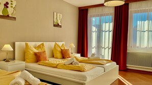 A hotel room with two beds, a large window with red curtains, and artwork on the walls. - Landhaus Mitsche, Gartnerkofel apartment with mountain views (Radnig)