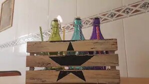 Una caja de madera con un diseño de estrella en la parte superior, que contiene botellas de colores.