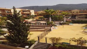 Un patio de hotel con piscina, palmeras y una escalera que lleva a los pisos superiores.