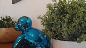 Una figurita de elefante azul de cerámica junto a una planta en maceta sobre una superficie de madera.