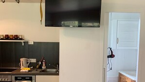 Une cuisine moderne équipée d’un lave-vaisselle, d’un four et d’un téléviseur à écran plat fixé au mur.