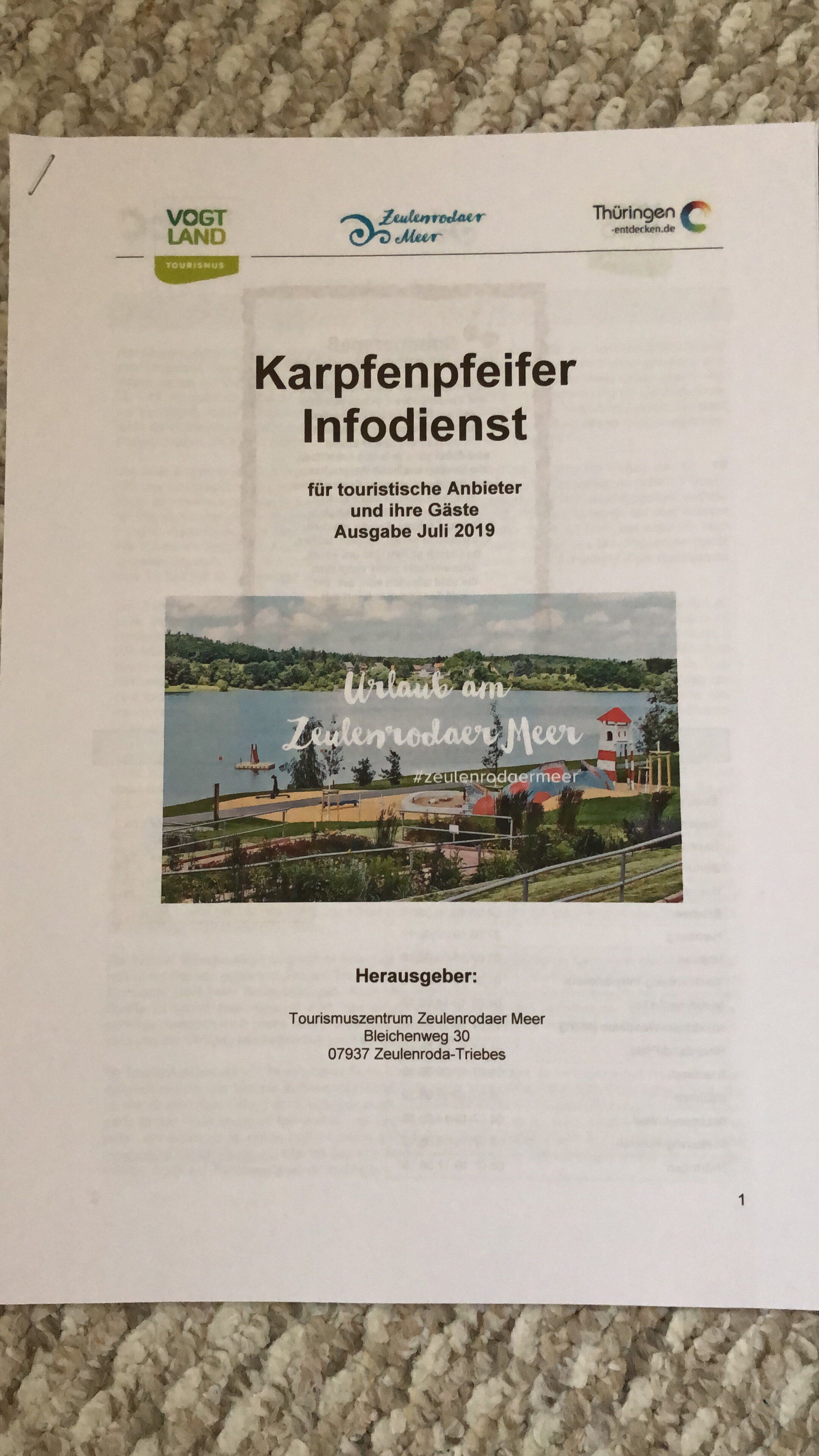 A brochure titled "Karpfenpeifer Infodienst für touristische Anbieter und ihre Gäste Ausgabe Juli 2019" with a scenic view of a lake and a red-roofed building.