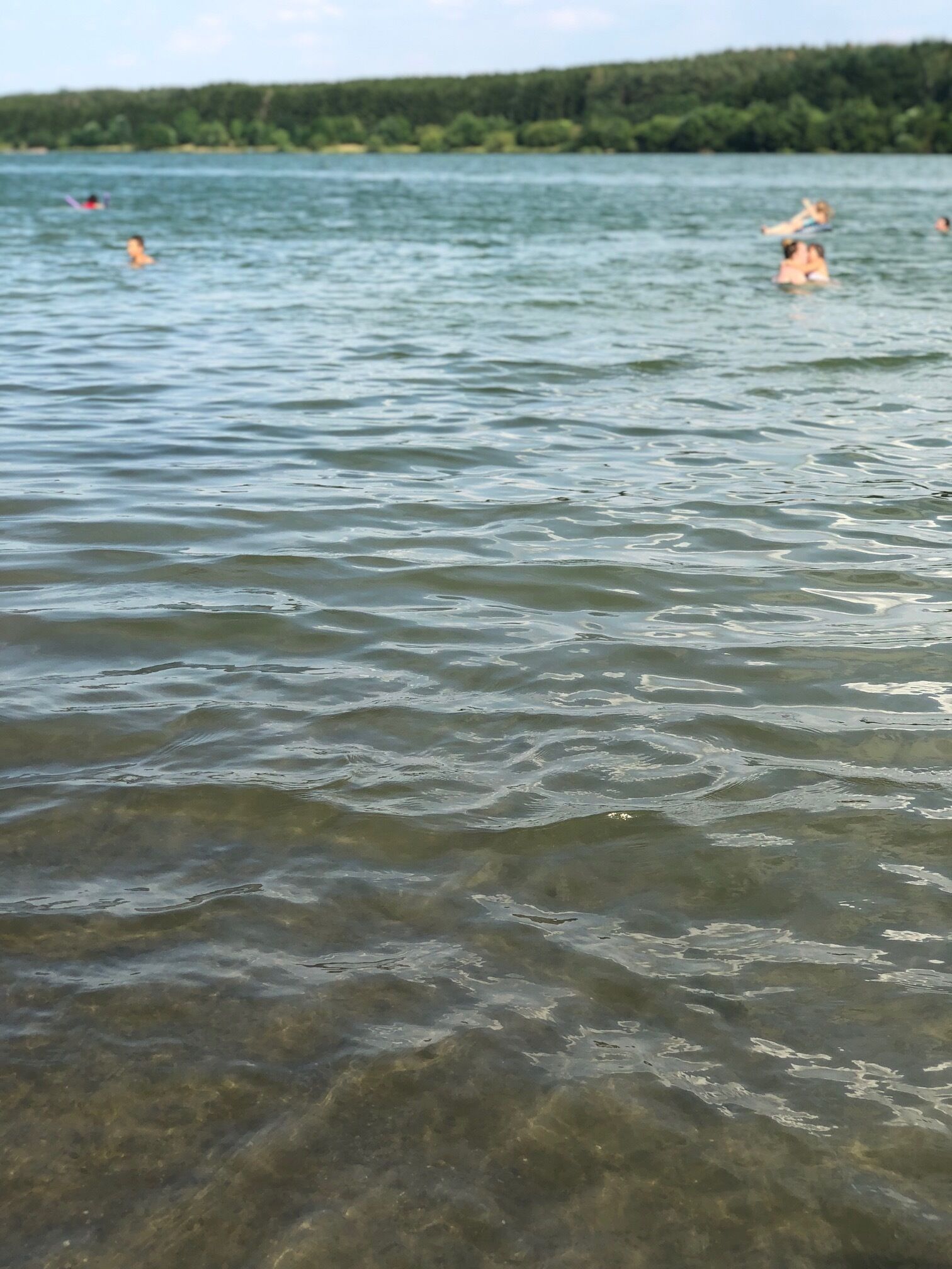 Un lago con agua cristalina y gente nadando.