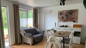 Une pièce chaleureuse avec un canapé, une table à manger, des chaises et une carte du monde accrochée au mur.