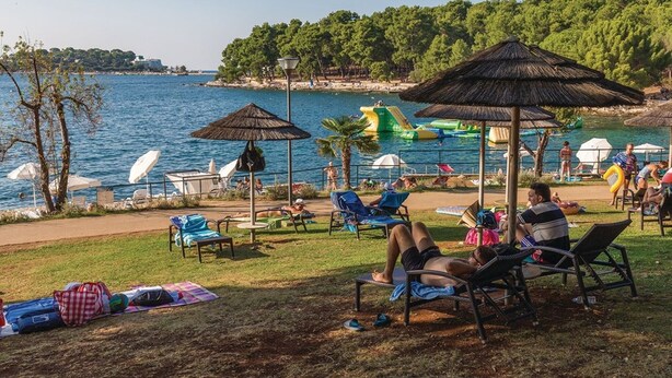 A beachside area with lounge chairs, umbrellas, and a pool area with inflatable slides. - Beautiful villa with pool, KA, barbecue, WLAN, suitable for families (Fuskulin)