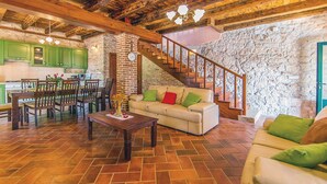 A spacious living area with a wooden staircase, a sofa with green cushions, and a dining set. - Beautiful villa with pool, KA, barbecue, WLAN, suitable for families (Fuskulin)