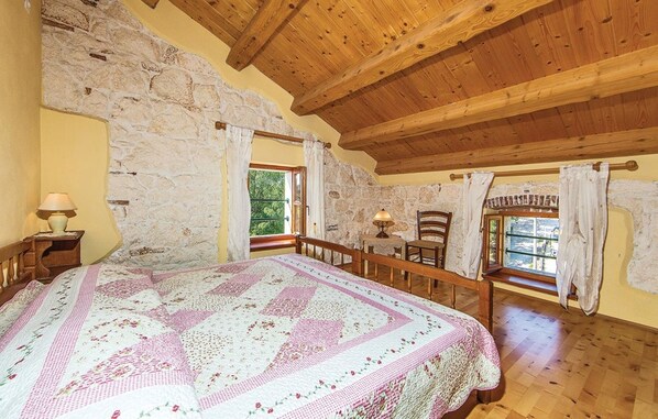 A bedroom with a large bed, stone walls, wooden beams, and two windows with curtains. - Beautiful villa with pool, KA, barbecue, WLAN, suitable for families (Fuskulin)