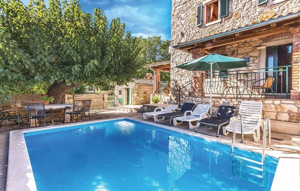 A swimming pool with lounge chairs and an umbrella, surrounded by stone buildings and greenery. - Beautiful villa with pool, KA, barbecue, WLAN, suitable for families (Fuskulin)