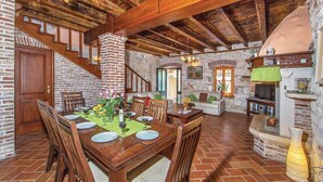 A rustic dining area with a wooden table set for four, surrounded by stone walls and a wooden staircase. - Beautiful villa with pool, KA, barbecue, WLAN, suitable for families (Fuskulin)