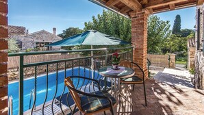 A balcony with a pool, a table with chairs, and a green umbrella. - Beautiful villa with pool, KA, barbecue, WLAN, suitable for families (Fuskulin)