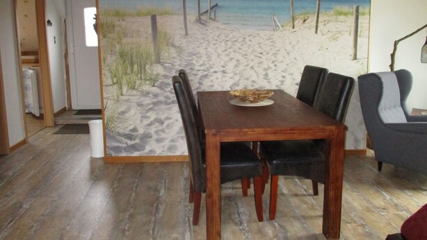 A dining area with a beach mural, wooden table, and chairs.