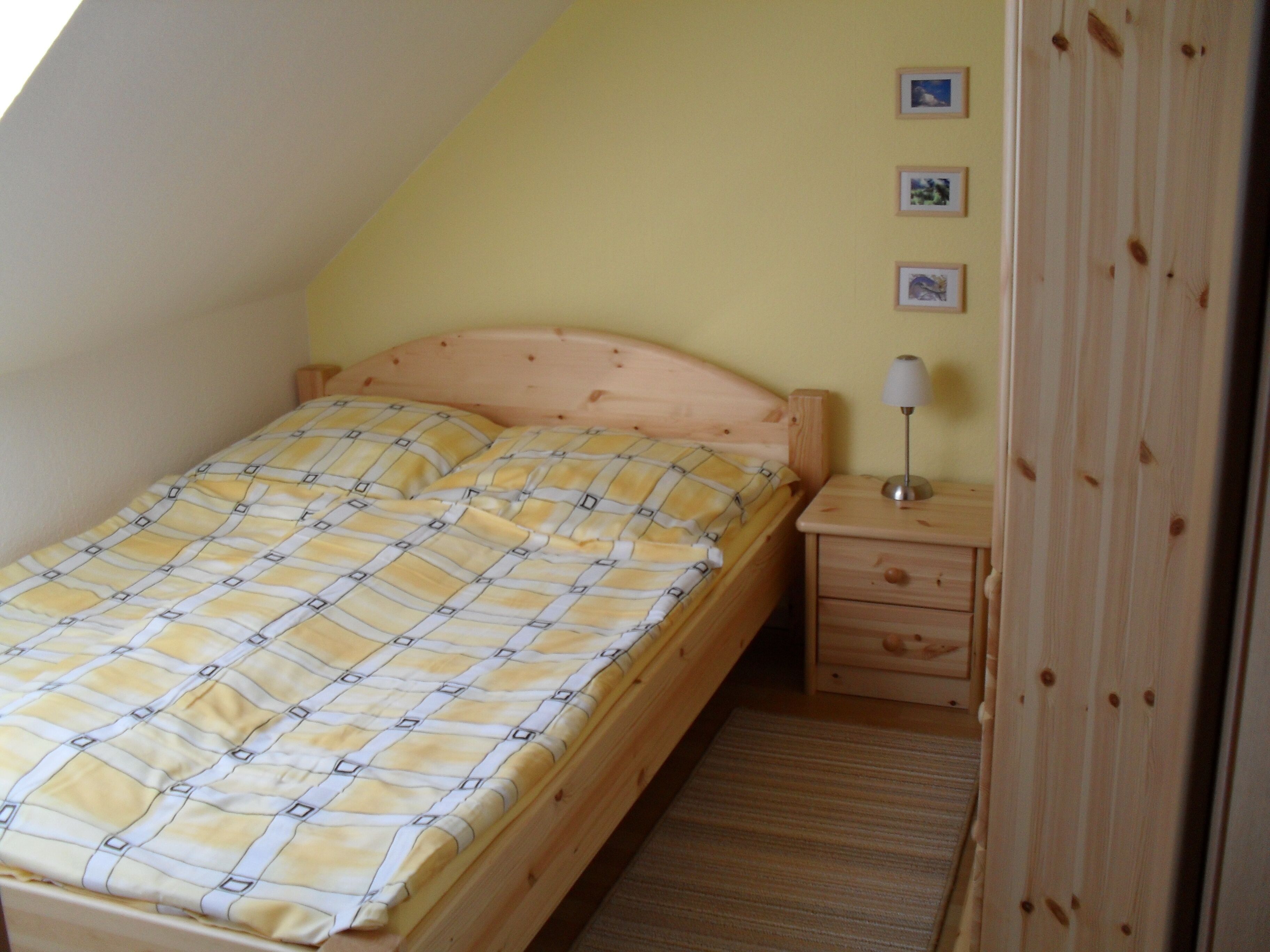 Une chambre à coucher avec un lit, une table de chevet en bois et une lampe.